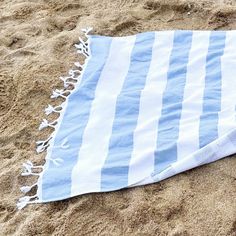 a blue and white towel laying on top of a sandy beach