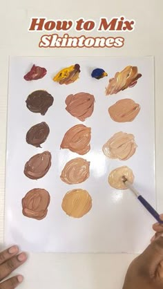 someone is holding a paintbrush and painting on a sheet of paper with different colors