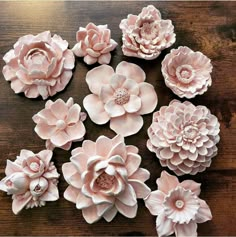 several pink flowers are arranged on a wooden table, one is larger than the other