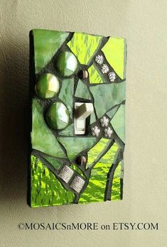 a light switch cover with green and white designs on it's side, mounted to the wall