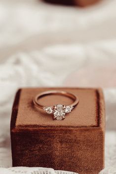 an engagement ring sitting on top of a wooden box next to a lace covered tablecloth