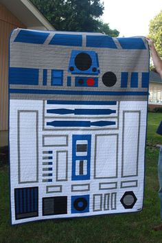 a young boy standing in front of a cardboard star wars r2d2 sign