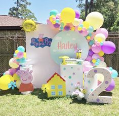 an outdoor birthday party with balloons, decorations and peppo the pig cake topper