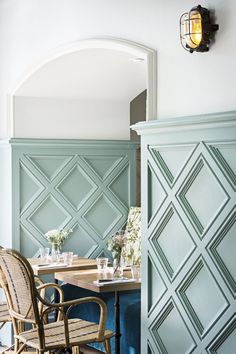 the interior of a restaurant with blue walls and wooden tables, chairs and vases