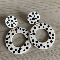 two pairs of white and black polka dot earrings on top of a wooden table,