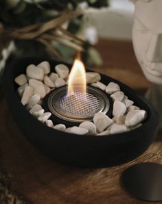 a lit candle sitting on top of a wooden table next to rocks and a vase