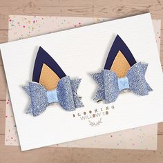 two blue bows are on top of a card with confetti sprinkles