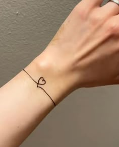 a woman's wrist with a small heart tattoo on it