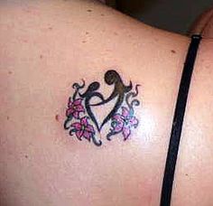 a woman's back with a tattoo on her left shoulder and pink flowers in the shape of a heart