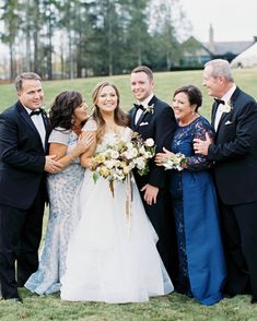 a group of people standing next to each other on top of a grass covered field