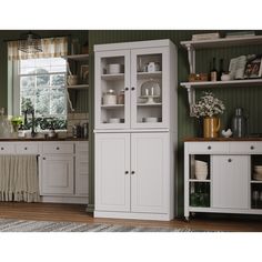 a kitchen with green walls and white cupboards in the center, along with an area rug on the floor