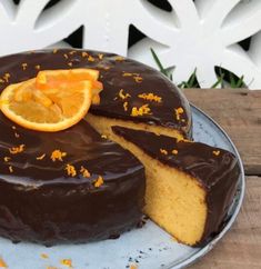 a chocolate cake with an orange slice cut out of it on a blue platter