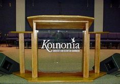 a wooden podium with speakers on it in front of a sign that says kolonna