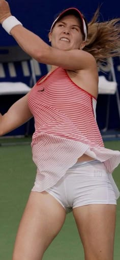 a woman swinging a tennis racquet on top of a tennis court