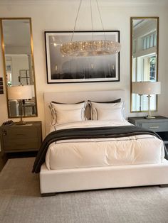 a bedroom with a large bed, mirror and chandelier hanging above the bed