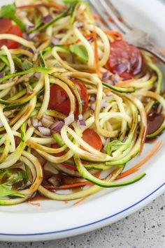 a white plate topped with zucchini and veggies next to a fork