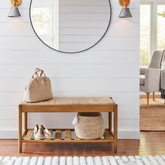 a wooden bench sitting under a round mirror next to a white rug and lamp shades