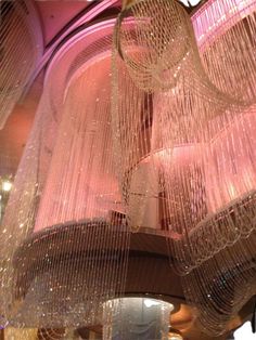 a chandelier hanging from the ceiling in a building with pink lights and decorations