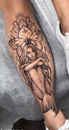 a woman's leg with a tattoo on it and a mermaid holding a flower