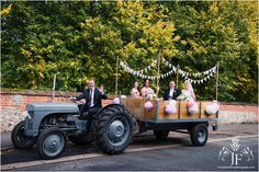 a bride and groom riding on the back of an old tractor with their bridal party