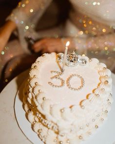 a white cake with the number sixty on it and a candle in the shape of a heart