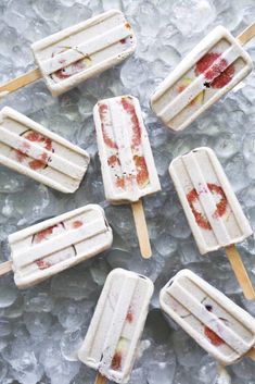 five popsicles with strawberries on them are sitting on an ice - covered surface