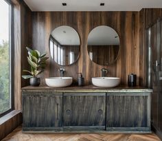 a bathroom with two sinks and mirrors on the wall next to a large wooden cabinet