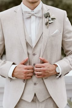 a man in a suit and bow tie is holding his hands on his lapel