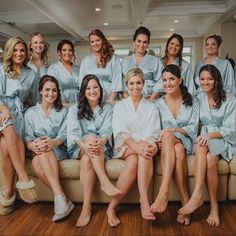 a group of women sitting on top of a couch wearing blue robes and slippers