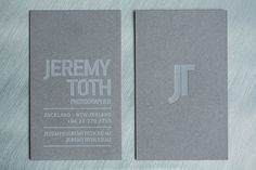 two business cards sitting side by side on top of a metal surface with the letter j