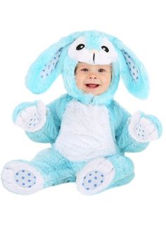 a baby in a blue bunny costume sitting on the floor with his hands up and smiling