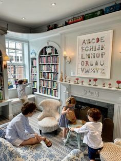 two children sitting on chairs in front of a fire place with bookshelves behind them