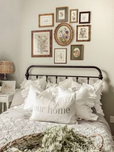 a bed with pillows and pictures on the wall above it, along with a wicker basket