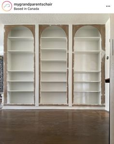 an empty room with white bookcases and wood flooring in the middle of it