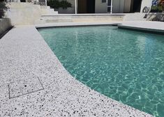 a swimming pool with clear blue water and steps leading up to the house in the background