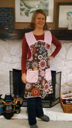 a woman wearing an apron standing in front of a fire place with her hands on her hips