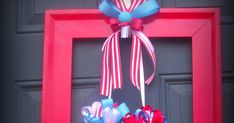 a red, white and blue wreath hanging on a door frame with an american flag bow