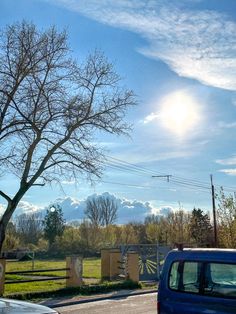 a blue van driving down a street next to a tree