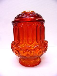 an orange glass vase sitting on top of a white table