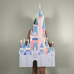 a woman holding up a cut out of a castle