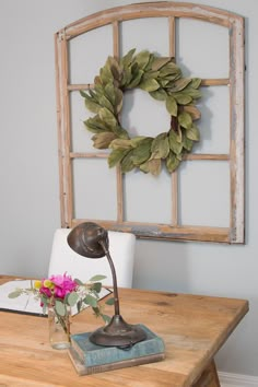 a wooden table topped with a lamp next to a wreath on top of a wall