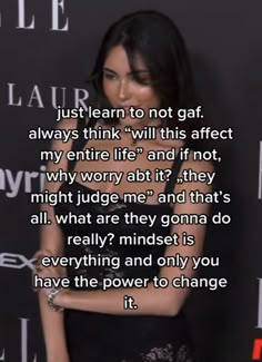 a woman standing in front of a black wall with a quote on it that reads, just learn to not gaf