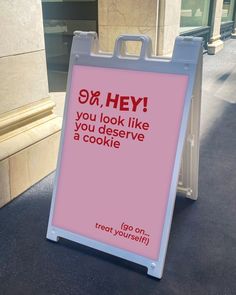 a sign that is on the ground in front of a building saying, hey you look like you deserves a cookie