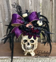 a skull with purple and black flowers on it's head sitting on a shelf