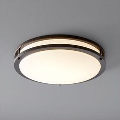 a circular light fixture on the ceiling in a room with gray walls and flooring