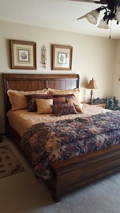 a large bed in a bedroom next to two lamps and pictures on the wall above it