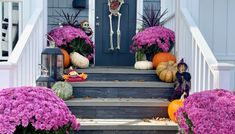 halloween decorations on the steps of a house with purple flowers and pumpkins in front