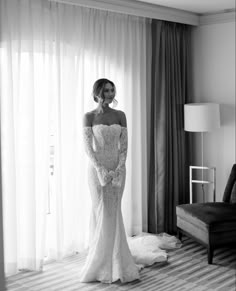 a woman in a wedding dress standing next to a couch