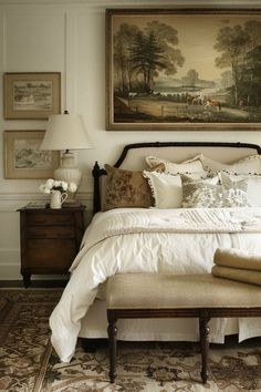 a bed with white sheets and pillows in a bedroom next to a painting on the wall