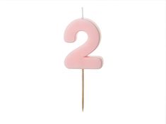 a pink candle with the number two on it's stick in front of a white background